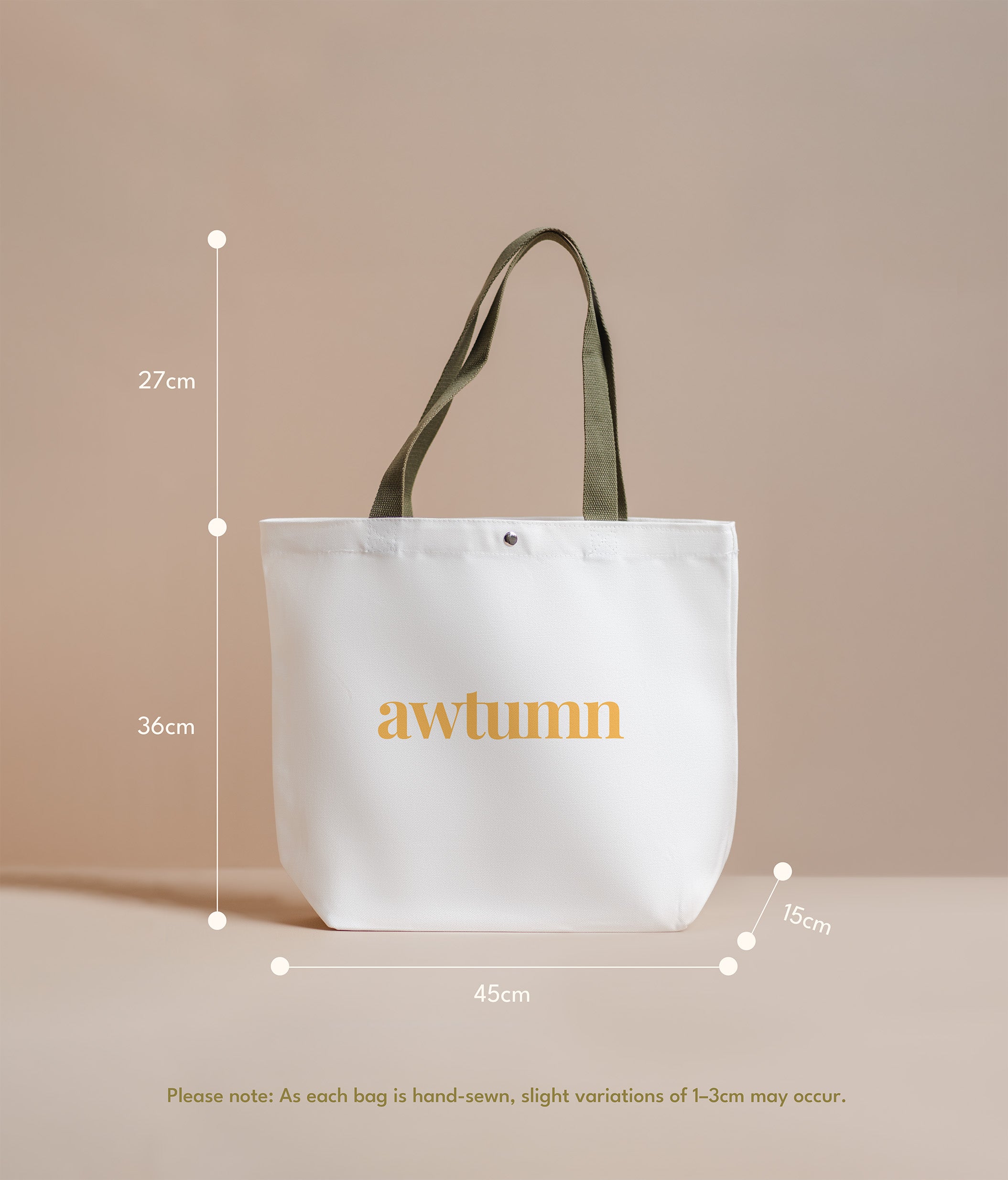 White tote bag with 'awtumn' text and measurements on a beige background