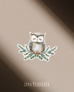 Illustration of an owl on a branch with leaves, set against a beige background with 'awtumn' text.