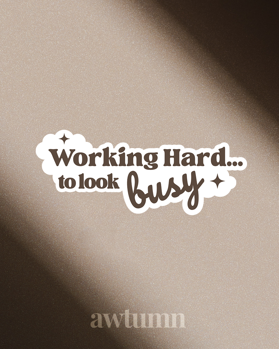 Sticker with text 'Working Hard... to look busy' on a textured beige background
